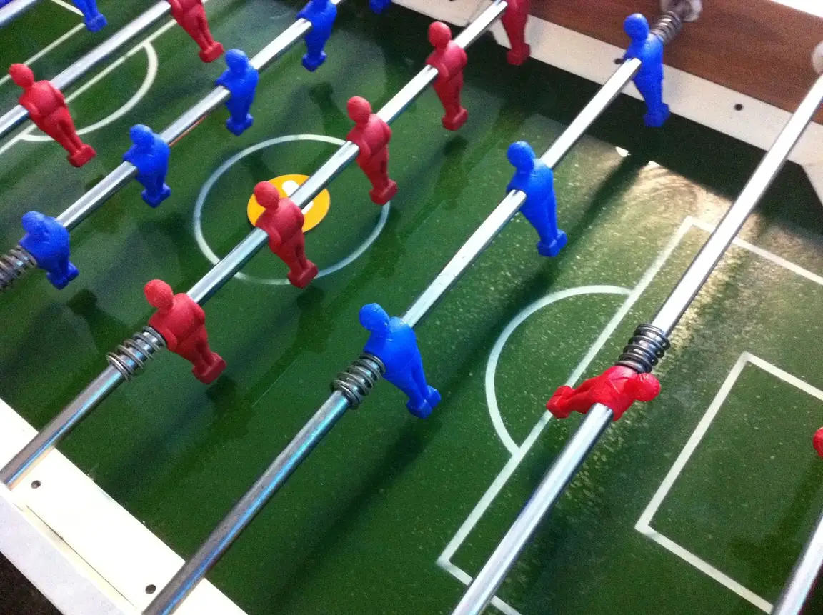 Tischfußball-Tisch mit roten und blauen Figuren, von schräg oben